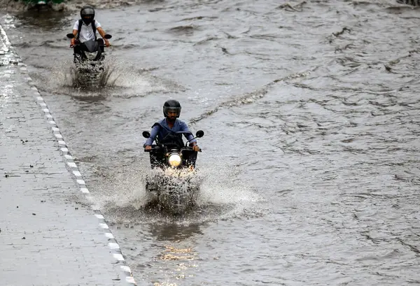 NEW DELHI, INDIA - 10 Temmuz 2023 'te Hindistan' ın Yeni Delhi kentinde şiddetli yağmurların şehri kasıp kavurmasından sonra, banliyö sakinleri su dolu bir caddede hareket ediyor.. 