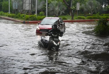 NOIDA, INDIA - 26 Temmuz 2023 'te Hindistan' ın Noida kentinde, 44. Sektörde, çok sular altında kalmış bir yoldan geçtiler. Delhi-NCR sakinleri şiddetli yağış gördü. Banliyö sakinleri çeşitli alanlarda su bloklama nedeniyle sorunlarla karşılaştı. 