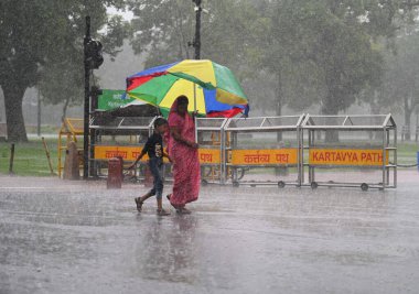 NEW DELHI, INDIA - 10 Temmuz 2023 tarihinde Yeni Delhi, Hindistan 'da Kartvaya Yolu' nda sağanak yağmur sırasında ziyaretçiler. Hindistan 'ın kuzeybatısında 40 yıllık bir rekor kıran şiddetli bir yağmura tanık oldu..