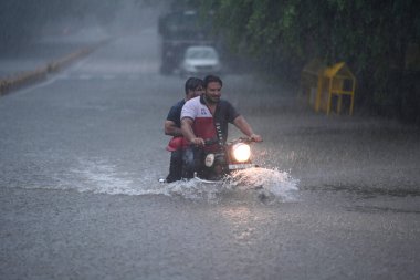 NEW DELHI, INDIA - 9 Temmuz 2023 'te Hindistan' ın Yeni Delhi kentinde, Anayasa Mahkemesi 'nde yoğun yağmurlar altında, banliyö sakinleri uzun bir yolda hareket ediyorlar. Delhi-NCR, Cuma, Cumartesi ve Pazar gecelerinde şiddetli yağmurdan sırılsıklam olmuştu. T