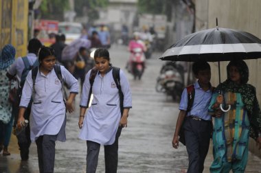 GURUGRAM, INDIA - 20 Temmuz: Öğrenciler 27 Temmuz 2023 'te Hindistan' ın Gurugram kentindeki Devlet Hastanesi yakınlarındaki Basai Road 'da muson yağmurları altında evlerine dönüyorlar. (Fotoğraf: Parveen Kumar / Hindustan Times)