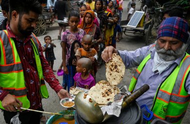 NEW DELHI, INDIA - 15 Temmuz 2023 tarihinde, Yeni Delhi, Hindistan 'da, Yamuna Bank Metro İstasyonu Kampı' nda, Yamuna Nehri 'nin su seviyesi yükseldikten sonra selden etkilenen insanlara yiyecek ve diğer yardım materyalleri dağıtıyorlar. R 'nin su seviyesi