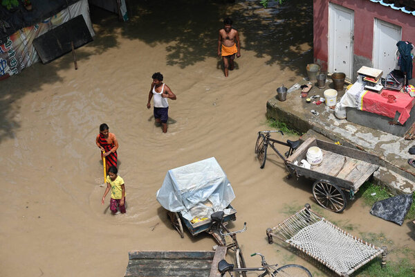 NEW DELHI, INDIA - JULY 15: People wade through a flooded road after the water level of the river Yamuna rose following heavy monsoon rains, at Mayur Vihar Side on July 15, 2023 in New Delhi, India. 