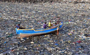 MUMBAI, INDIA - 5 Haziran 2024 'te Hindistan' ın Mumbai kentinde, Dünya Çevre Günü Colaba 'da, Badhwar Park yakınlarında tonlarca plastik atık arasında balıkçı teknesini tırmandırmaya hazırlanan balıkçılar,. 