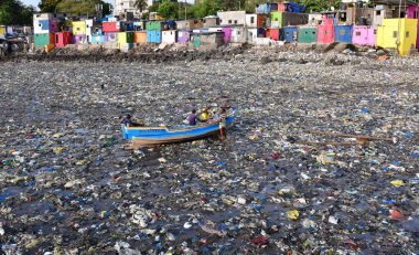 MUMBAI, INDIA - 5 Haziran 2024 'te Hindistan' ın Mumbai kentinde, Dünya Çevre Günü Colaba 'da, Badhwar Park yakınlarında tonlarca plastik atık arasında balıkçı teknesini tırmandırmaya hazırlanan balıkçılar,. 