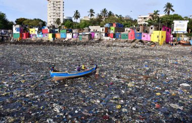 MUMBAI, INDIA - 5 Haziran 2024 'te Hindistan' ın Mumbai kentinde, Dünya Çevre Günü Colaba 'da, Badhwar Park yakınlarında tonlarca plastik atık arasında balıkçı teknesini tırmandırmaya hazırlanan balıkçı,. 