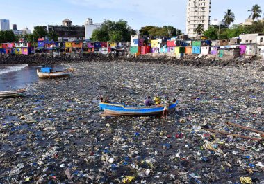 MUMBAI, INDIA - 5 Haziran 2024 'te Hindistan' ın Mumbai kentinde, Dünya Çevre Günü Colaba 'da, Badhwar Park yakınlarında tonlarca plastik atık arasında balıkçı teknesini tırmandırmaya hazırlanan balıkçılar,. 