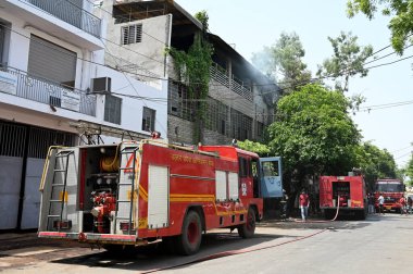 NOIDA  INDIA - JUNE 3  2024  Fire brigade personnel extinguish the fire at a garment factory in Sector 10  on June 3  2024 in Noida  India. During the investigation  it came to light that the fire broke out due to a short-circuit in the AC  and later clipart