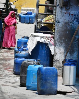 NEW DELHI, INDIA - 5 Haziran 2024 Yeni Delhi, Hindistan 'da 5 Haziran 2024 tarihinde Vasant Vihar yakınlarındaki Kusumpur Pahari' de su tankeri bekleyen evlerin önündeki boş konteynırlar. Delhi 'de Chanakyapuri' nin Sanjay Kamp alanı ve Ge bölgesi de dahil olmak üzere birkaç bölge.