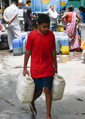 NEW DELHI, INDIA - JUNE 5 2024 People filling empty containers from a water tanker at Kusumpur Pahari near Vasant Vihar, on June 5, 2024 in New Delhi, India. Several areas in Delhi including Chanakyapuri's Sanjay Camp area and the Geeta colony area a clipart