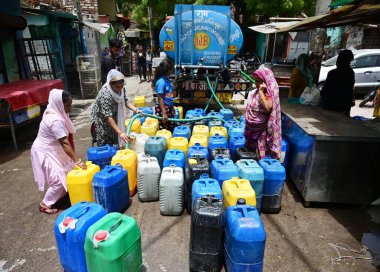 NEW DELHI, INDIA - JUNE 5 2024 People filling empty containers from a water tanker at Kusumpur Pahari near Vasant Vihar, on June 5, 2024 in New Delhi, India. Several areas in Delhi including Chanakyapuri's Sanjay Camp area and the Geeta colony area a clipart