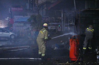NOIDA INDIA 12 Haziran 2024 itfaiye personeli Noida Hindistan 'da 12 Haziran 2024 tarihinde 37. bölgedeki benzin pompasının yanındaki dükkandaki yangını söndürdü. İki saat aralıksız ateş püskürtüldükten sonra on kadar ihale hızla oraya gider ve alevleri söndürür.