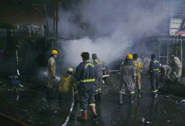 NOIDA INDIA 12 Haziran 2024 itfaiye personeli Noida Hindistan 'da 12 Haziran 2024 tarihinde 37. bölgedeki benzin pompasının yanındaki dükkandaki yangını söndürdü. İki saat aralıksız ateş püskürtüldükten sonra on kadar ihale hızla oraya gider ve alevleri söndürür.