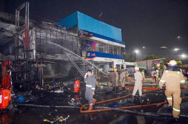 NOIDA INDIA 12 Haziran 2024 itfaiye personeli Noida Hindistan 'da 12 Haziran 2024 tarihinde 37. bölgedeki benzin pompasının yanındaki dükkandaki yangını söndürdü. İki saat aralıksız ateş püskürtüldükten sonra on kadar ihale hızla oraya gider ve alevleri söndürür.