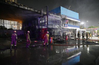 NOIDA INDIA 12 Haziran 2024 itfaiye personeli Noida Hindistan 'da 12 Haziran 2024 tarihinde 37. bölgedeki benzin pompasının yanındaki dükkandaki yangını söndürdü. İki saat aralıksız ateş püskürtüldükten sonra on kadar ihale hızla oraya gider ve alevleri söndürür.