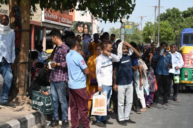 NEW DELHI INDIA 13 HAZİRAN 2024 LNJP Hastanesi hastaları hizmetkarları ve DTC yolcuları ile birlikte 13 Haziran 2024 'te Asıf Ali Yolu' nda sıcak bir yaz öğleden sonra, Yeni Delhi Hindistan 'da bir ağaç gölgesi altında duruyorlar. Fotoğraf: Sonu Mehta / Hindustan Times 