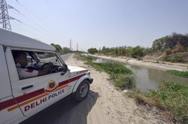 NEW DELHI INDIA 13 Haziran 2024 Delhi polis memurları 13 Haziran 2024 tarihinde Yeni Delhi Hindistan 'da Khera Kalan' da Munak kanalı boyunca devriye geziyorlar. Polis personelinin kanal boyunca konuşlandırılması, Çarşamba günü Yüksek Mahkeme 'nin doğrudan bir bağlantı iddiasına girmesi sonrasında gerçekleşti.