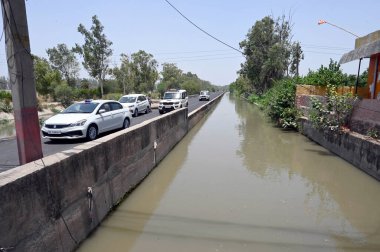 NEW DELHI INDIA 13 Haziran 2024 Delhi polis memurları 13 Haziran 2024 tarihinde Yeni Delhi Hindistan 'da Harevali' de Munak kanalı boyunca devriye geziyorlar. Kanal boyunca polis personelinin görevlendirilmesi, Çarşamba günü Yüksek Mahkeme 'nin aralarında doğrudan bir bağlantı kurması sonrasında gerçekleşti.