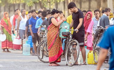 NEW DELHI INDIA: 14 Haziran 2024 - Yeni Delhi, Hindistan 'da 14 Haziran 2024 tarihinde Mayur Vihar yakınlarındaki Chilla Village' da yaşanan su krizleri sırasında Delhi Jal Board tankerinden su dolduran insanlar.  