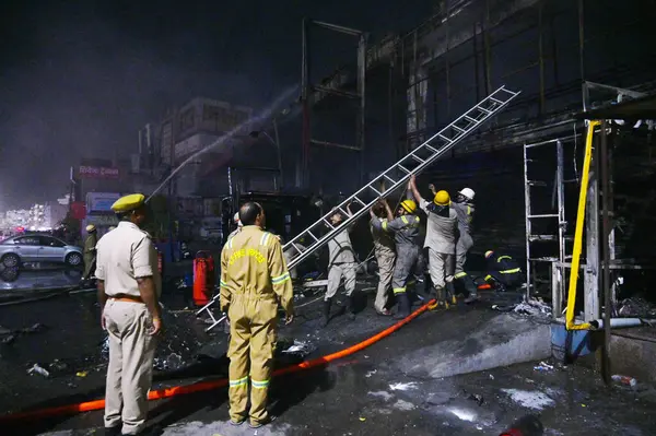 NOIDA INDIA 12 Haziran 2024 itfaiye personeli Noida Hindistan 'da 12 Haziran 2024 tarihinde 37. bölgedeki benzin pompasının yanındaki dükkandaki yangını söndürdü. İki saat aralıksız ateş püskürtüldükten sonra on kadar ihale hızla oraya gider ve alevleri söndürür.