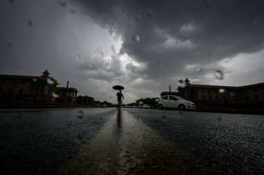 YENİ DELHI INDIA 16 HAZİRAN 2023 Bir adam, yağmurlu bir günde Vijay Chowk 'un üzerinde kara bulutların altında yürür Yeni Delhi' de 16 Haziran 2023 Hindistan Meteoroloji Bölümü, Perşembe günü Delhi NCR 'de şiddetli rüzgarlarla hafif yağmur öngörmüştü.