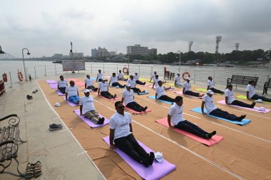 KOLKATA INDIA JUNE 21 2023 Port Trust officials participate in an event on the occasion of 9th International Day of Yoga on board P S Bhopal at Outram Jetty on banks of river Hooghly against backdrop of iconic Howrah Bridge on June 21 2023 in Kolkata clipart