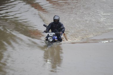 GURUGRAM INDIA 25 HAZİRAN 2023 Bir motorcu, 25 Haziran 2023 'te Narsinghpur köyü yakınlarındaki NH 48 servis yolunda yoğun yağmurlu bir yolda yürüdü. Gurugram Hindistan' da şiddetli yağış ve yıldırımlar eşliğinde ulusal kapağın çeşitli bölümlerini vurdu.