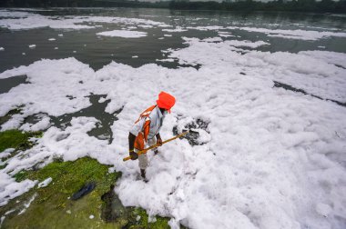 NEW DELHI INDIA JUNE 26 2023 A PWD worker cleans the banks of the Yamuna river laden with toxic foam at ITO on June 26 2023 in New Delhi India Photo by Raj K Raj Hindustan Times  clipart