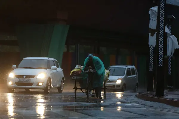 stock image NEW DELHI INDIA JUNE 25 2023 A rickshaw puller covered with plastic sheet passing during Rain near Lajpat Nagar on June 25 2023 in New Delhi India Heavy rainfall accompanied by lightning lashed several parts of the national capital Delhi and its adjo