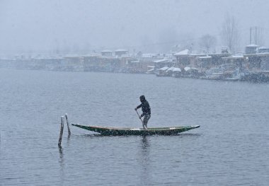 SRINAGAR INDIA FEBRUARY 4 2024 Bir kayıkçı 4 Şubat 2024 'te Srinagar Hindistan' da bir kar yağışı sırasında Dal Gölü 'nü geçiyor.