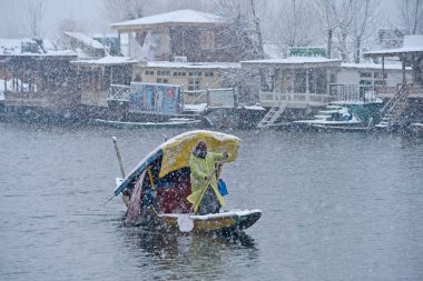 SRINAGAR INDIA FEBRUARY 4 2024 A boatman crosses Dal Lake during a snowfall on February 4 2024 in Srinagar India Several parts of Kashmir including Srinagar city witnessed fresh snowfall as the MeT department has forecast moderate topheavy snowfall i clipart