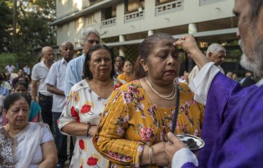 MUMBAI INDIA FEBRUARY 17 2024 An Indian Catholic Priest marks the symbol of the cross with ash on the foreheads of Christian people during an Ash Wednesday service at Canossa High School Mahim on February 17 2024 in Mumbai India Photo by Satish Bate  clipart