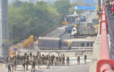 GHAZIABAD INDIA FEBRUARY 18 2024 Police personnel stand guard next to a barrier to prevent farmers protesting to demand minimum crop prices from marching towards the National capital at the Ghazipur border on February 18 2024 in Ghaziabad India Massi clipart