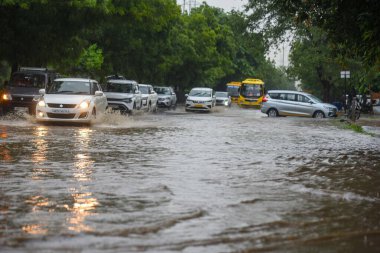 GURUGRAM, INDIA - 4 Eylül 2024 'te Gurugram, Hindistan' da, Subhash Chowk yakınlarındaki 33. bölgede, yağmurlu bir yolda araçlar su dolu bir yolda yürüdü. Delhi-NCR sakinleri ani bir değişikliğe tanık oldular