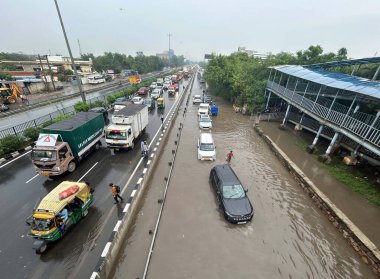 GURUGRAM, INDIA - 4 Eylül 2024 'te Gurugram, Hindistan' da, Subhash Chowk yakınlarındaki 33. bölgede, yağmurlu bir yolda araçlar su dolu bir yolda yürüdü. Delhi-NCR sakinleri ani bir değişikliğe tanık oldular
