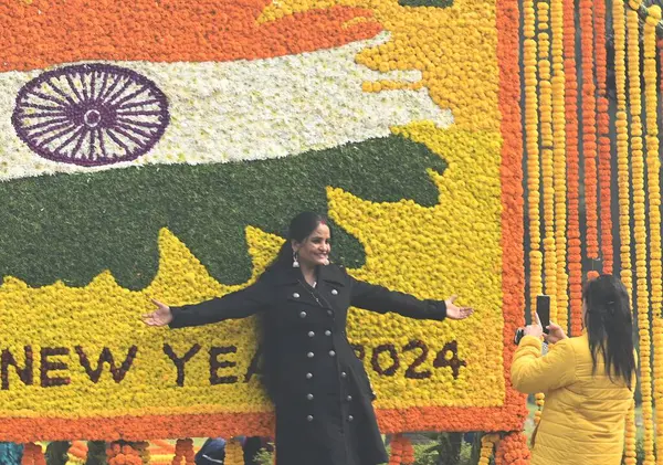 YENİ DELHI INDIA JANUARY 12024 İnsanlar Hindistan Kapısı ve Kartavaya Yolu 'nda toplanıp Vipin Kumar Hindustan Times' ın yeni yıl fotoğrafını kutlarken çiçek kalabalığı önünde selfie çekiyorlar. 