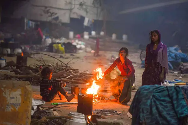 GURUGRAM INDIA HAZİRAN 32024 Evsiz insanlar, soğuk bir kış sabahı, Parveen Kumar Hindistan Times 'ın 48. Rajiv Chowk Fotoğrafı' ndaki üstgeçitte kendilerini ısıtmak için şenlik ateşinin etrafında otururlar. 