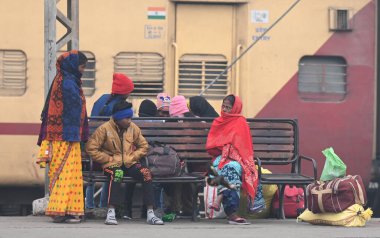 NEW DELHI INDIA HAZİRAN 5 2024 Yolcu bekleyen tren, kış sabahı Talik Köprüsü Tren İstasyonu 'nda kendilerini ısıtmak için yün giysiler giyer.