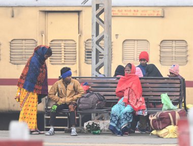 NEW DELHI INDIA HAZİRAN 5 2024 Yolcu bekleyen tren, kış sabahı Talik Köprüsü Tren İstasyonu 'nda kendilerini ısıtmak için yün giysiler giyer.