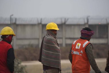 NEW DELHI INDIA JANUARY 7 2024 Construction worker wrap in shawls going to work on a cold winter morning at Dwarka Link Road South West Delhi near Samalka red light Foggy morning challenges Delhi NCR with intensifying cold wave mercury dips further a clipart