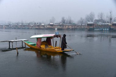 SRINAGAR INDIA JANUARY 6 2024 Bir kayıkçı Dal Gölü 'nün kısmen donmuş bir yüzeyi üzerinde kürek çekiyor 6 Ocak 2024 sabahı Srinagar Hindistan' da Srinagar sezonun en soğuk gecesini kaydetti
