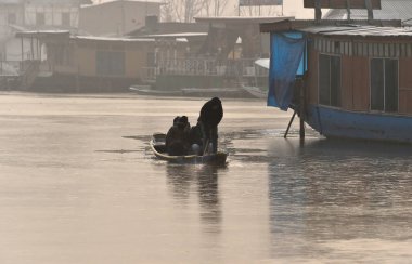 SRINAGAR INDIA JANUARY 6 2024 Bir kayıkçı Dal Gölü 'nün kısmen donmuş bir yüzeyi üzerinde kürek çekiyor 6 Ocak 2024 sabahı Srinagar Hindistan' da Srinagar sezonun en soğuk gecesini kaydetti