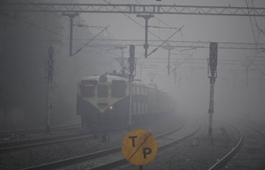 NEW DELHI INDIA 13 JANUARY 2024 Soğuk bir kış sabahı Tilak Brij Tren İstasyonu 'nda sisli bir kış sabahı görünürlüğü düşük bir tren yavaşça hareket ediyor. 