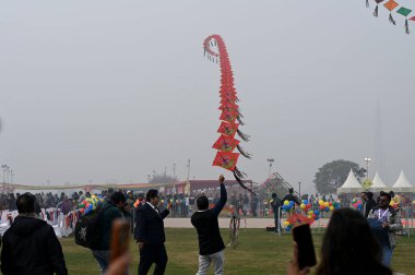 NEW DELHI INDIA JANUARY 13 2024 People flying kites during the first international kite festival Patang Utsav Inaugurated by Delhi LG VK Saxena at Baansera city first bamboo theme park at Sarai Kale Khan on the banks of river Yamuna clipart