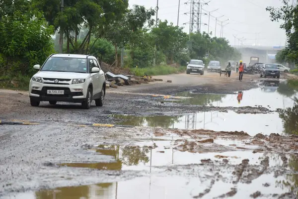 stock image GURUGRAM INDIA SEPTEMBER 6 2024 The 60 meter road opposite Sector 102 Oyster Grande is in very bad condition due to rain riddled with large potholes near Dwarka Expressway on September 6 2024 in Gurugram India Several areas in the capital were affect