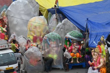 NEW DELHI INDIA 4 EPTEMBER 4 2024 Sanatçılar kendilerini Yeni Delhi 'de 4 Eylül 2024' te Ashok Park 'ta yağmurdan korumak için Tanrı Ganesh İdollerini plastikle kaplıyorlar. Delhi sakinleri, şiddetli yağmurun bazı bölgelerine vurduğu hava değişimine tanık oldular.