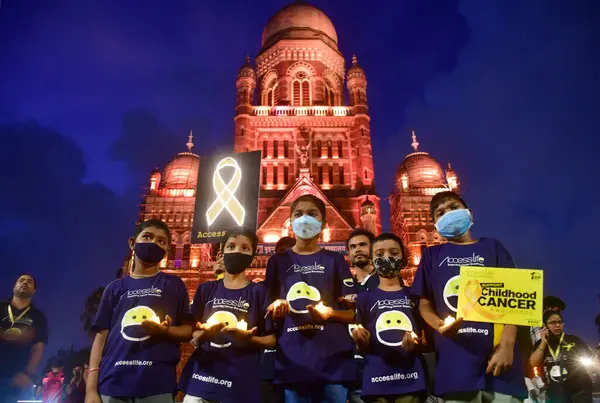 stock image MUMBAI INDIA SEPTEMBER 4 2024 Cancer affected children were seen holding candles in front of Mumbai two iconic sites Chhatrapati Shivaji Maharaj Terminus CSMT and Municipal Corporation of Greater Mumbai headquarters illuminated in golden colour in su