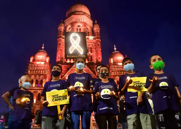 stock image MUMBAI INDIA SEPTEMBER 4 2024 Cancer affected children were seen holding candles in front of Mumbai two iconic sites Chhatrapati Shivaji Maharaj Terminus CSMT and Municipal Corporation of Greater Mumbai headquarters illuminated in golden colour in su