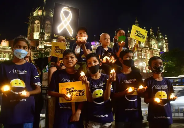 stock image MUMBAI INDIA SEPTEMBER 4 2024 Cancer affected children were seen holding candles in front of Mumbai two iconic sites Chhatrapati Shivaji Maharaj Terminus CSMT and Municipal Corporation of Greater Mumbai headquarters illuminated in golden colour in su