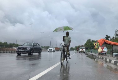 GURUGRAM INDIA 8 Temmuz 2023 Tau Devi Lal Stadyumu yakınlarındaki 32. Bölge 'de şemsiyeli bir adam cuma ve cumartesi gecesi Hindistan' ın Gurugram şehrinde bisiklet sürüyor.